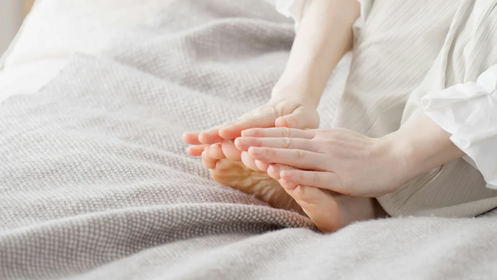 Person rubbing and warming cold bare feet with both hands