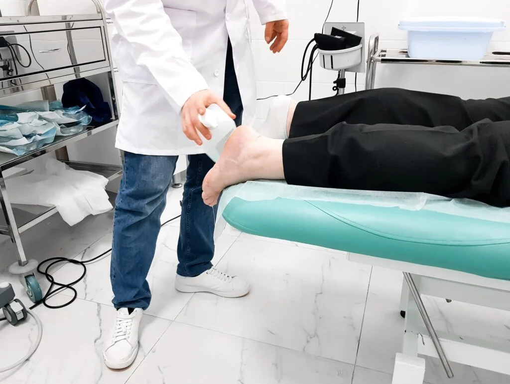 Doctor performing shockwave therapy on a patient's heel.