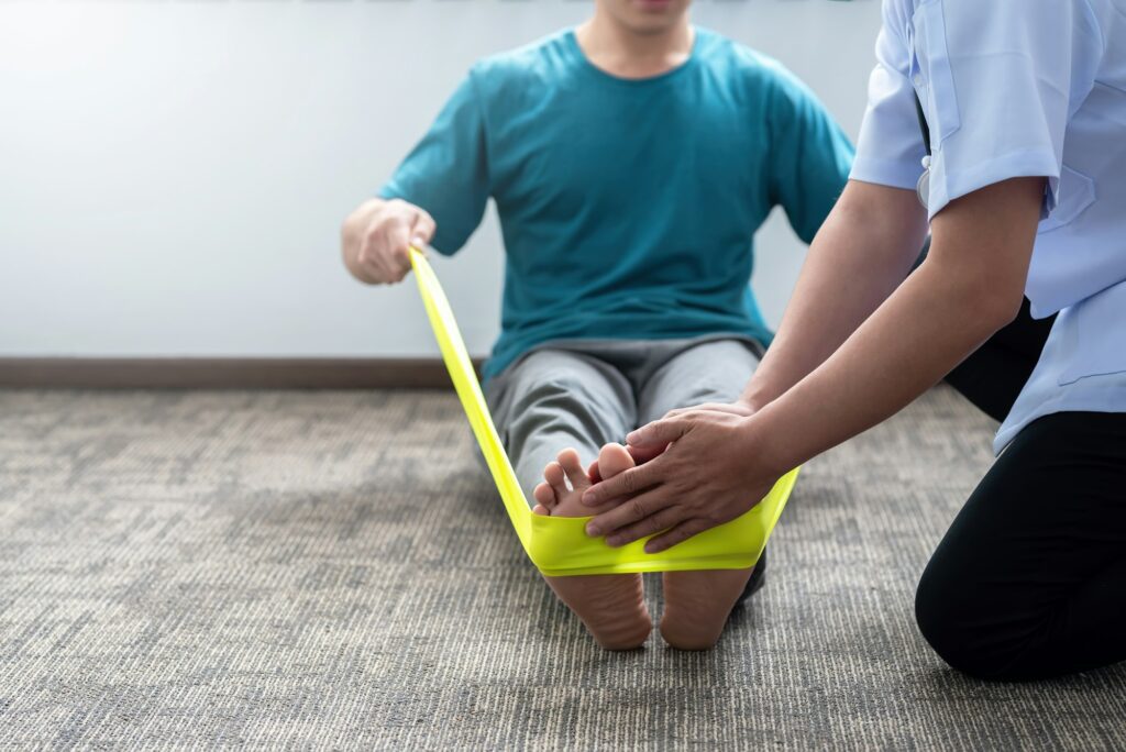 Physical therapist assisting a patient with foot rehabilitation using a resistance band.