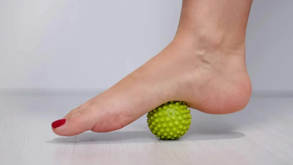 Person rolling the sole of their foot on a massage ball.